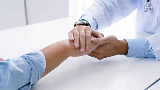 Arzt hält fürsorglich die Hand eines Kurgastes