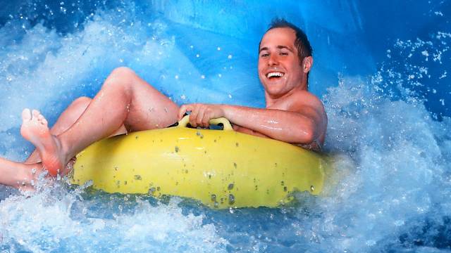 Mann auf gelben Reifen in einer Wasserrutsche