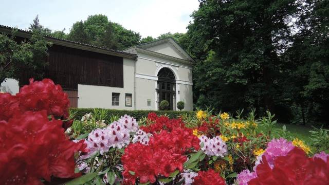 Frontansicht auf den Schwind-Pavillon Rüdigsdorf, im Vordergrund bunte Blumen