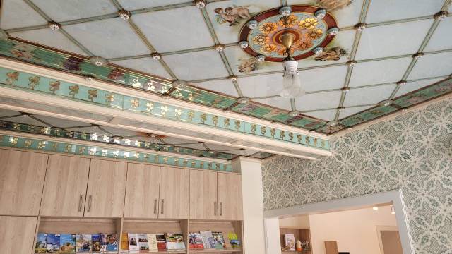 Aufwändig verzierte Glasdecke mit floralen Mustern und Putten – stilvolles Highlight im historischen Gebäude der Tourist-Information Bad Lausick.